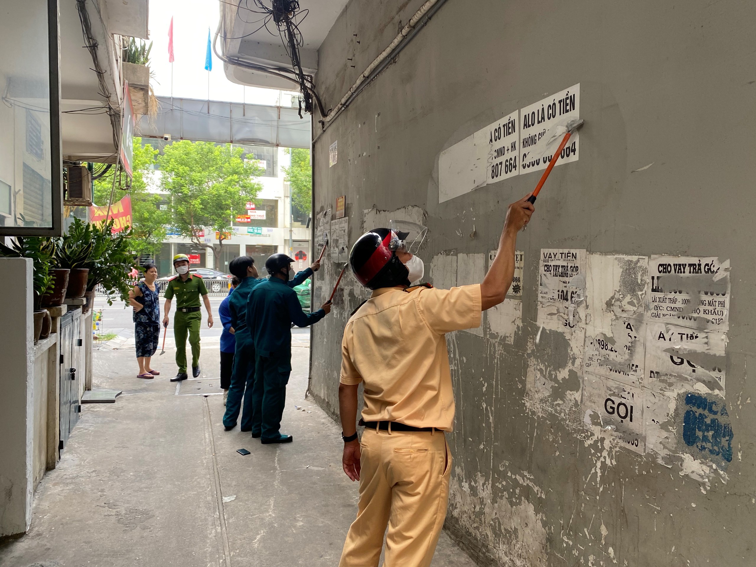 (Hình ảnh CBCS Đội CSGT Chợ Lớn phối hợp với lực lượng ĐVTN Phường 11, Quận 5 xóa quảng cáo trước 01 đường hẻm)