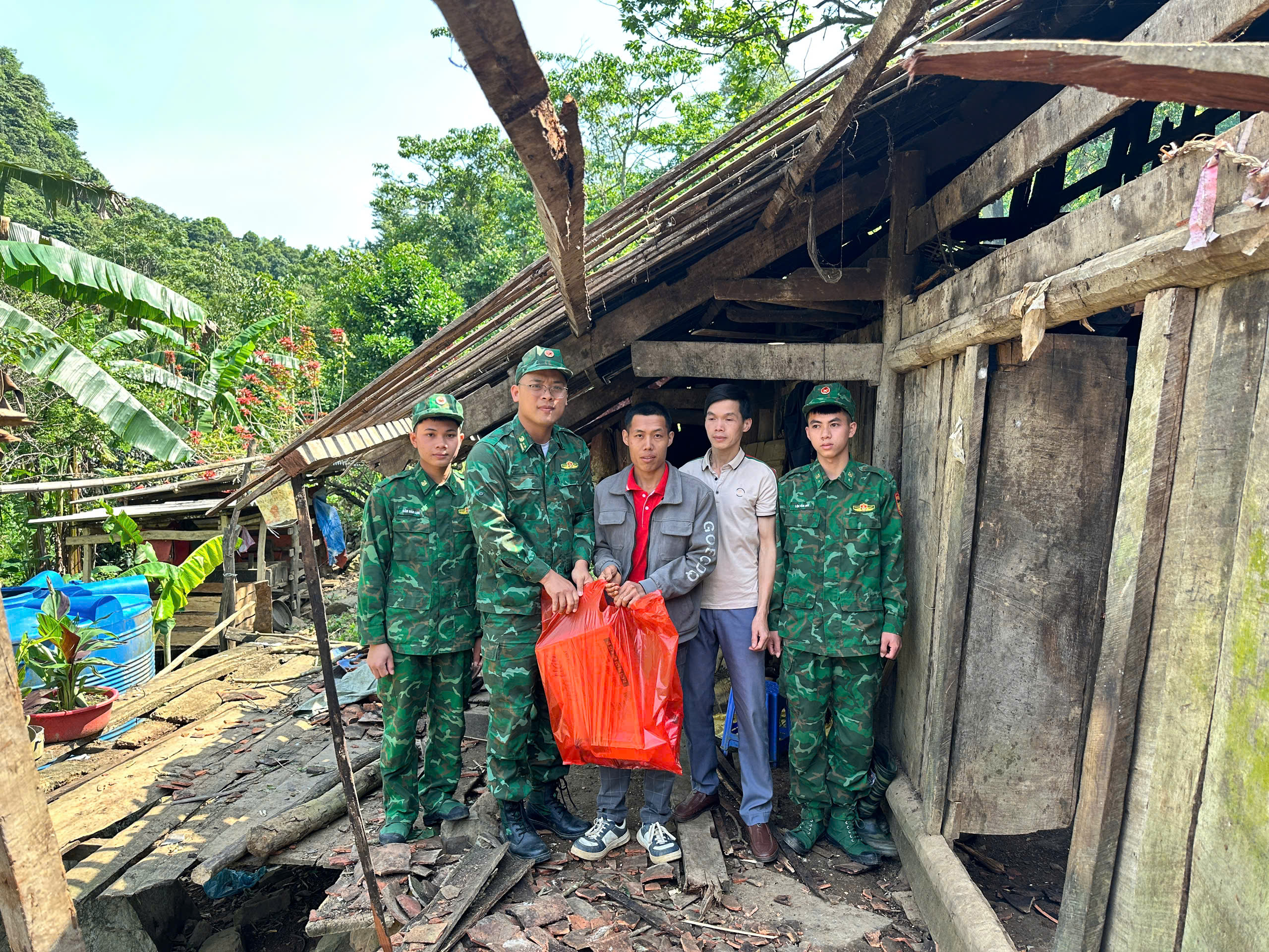 Đại diện lãnh đạo Đồn và chiến sĩ tặng quà cho người dân bản để khắc phúc khó khăn trước mắt. 