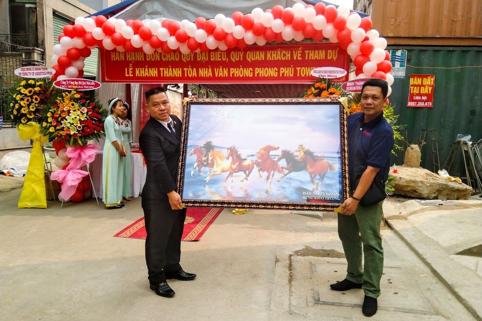 Ông Nguyễn Minh Luân(áo vest) nhận bức tranh mã đáo thành công do anh Hiền Thao đại diện doanh nghiệp dầu nhớt LOTOS trao tặng.