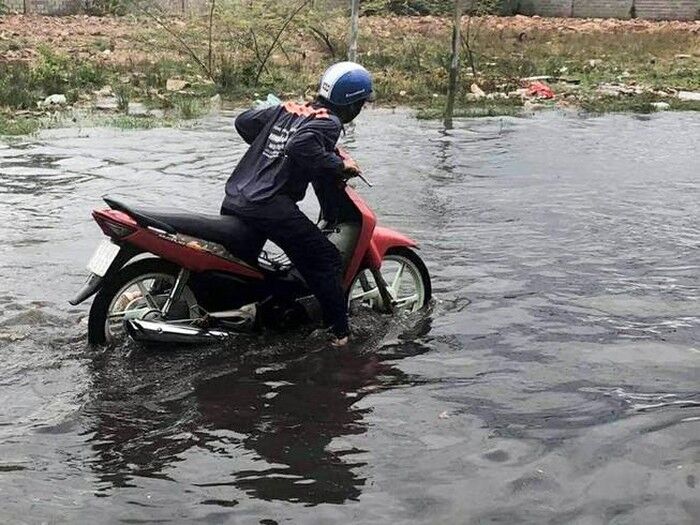 Mưa trái mùa làm ngập đường, người dân đi lại khó khăn trong sáng 7-4. Ảnh: TH