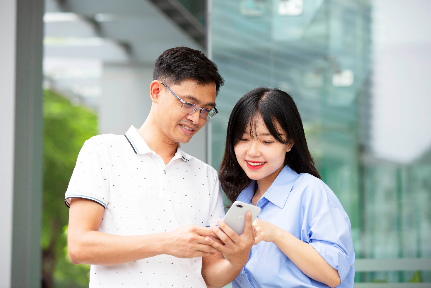 A person and person looking at a phone Description automatically generated